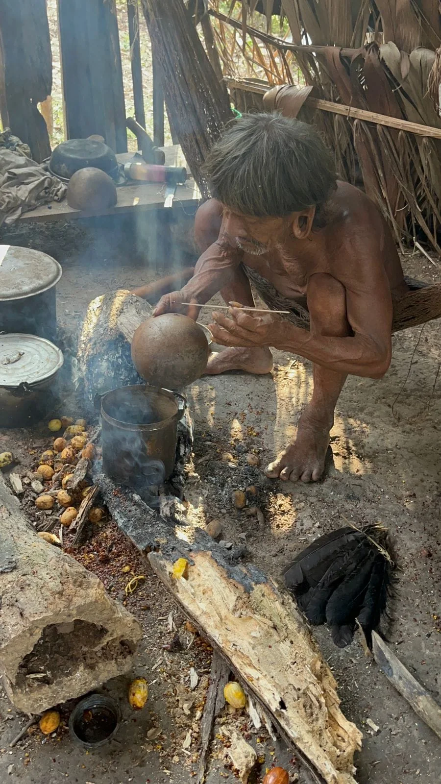A Waorani host beside a fire inside a shelter